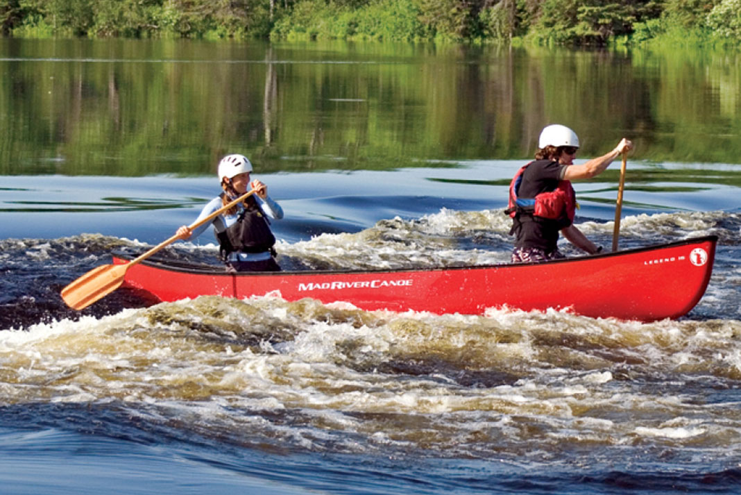 Man and woman tandem canoeing in the Mad River Legend 16 canoe