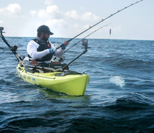 man fishes open water from a kayak rigged for ocean fishing