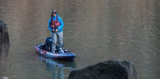 Man standing on kayak and fishing