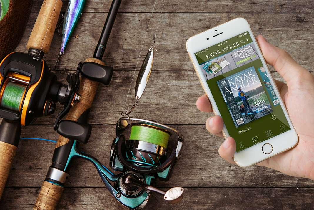 hand holding a phone with the Kayak Angler app beside some fishing rods