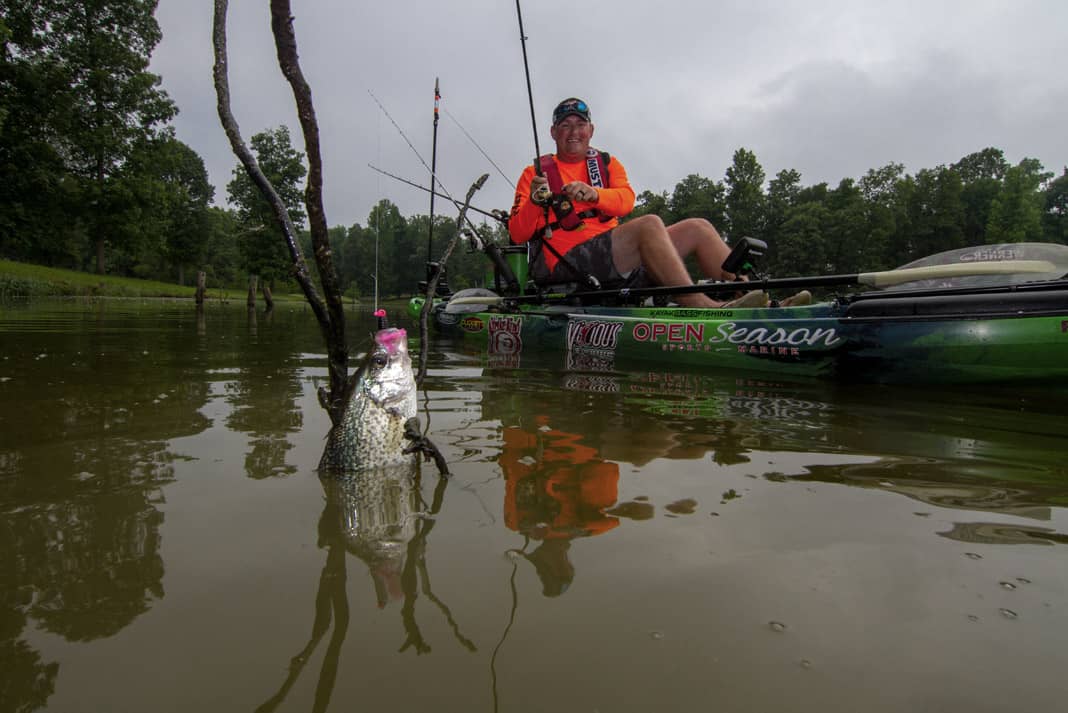 A man reels in a crappie while winter kayak fishing