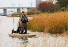 A fisherman stands and fishes among the grass in a Bonafide RS117 kayak