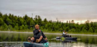 Two people casting while sitting on fishing kayaks