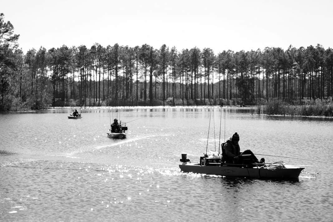 men kayak fishing on a lake surrounded by trees