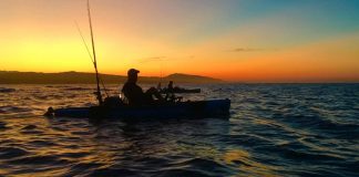 fisherman on his fishing kayak at sunset
