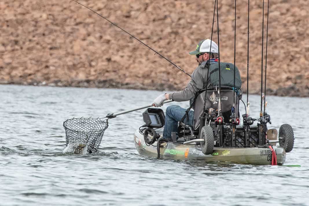 kayak angler uses a fishing net on the water