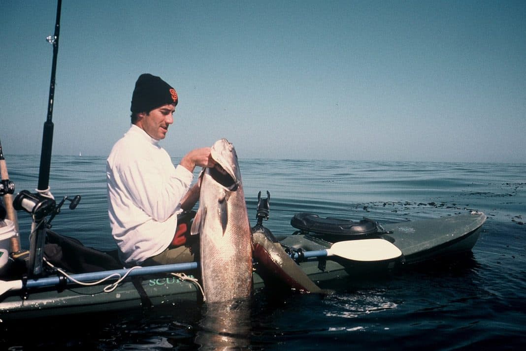 Adam Traubman holding a large fish from his fishing kayak