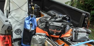 A selection of gear and tackle bags for kayak fishing sit in the bed of a pickup truck