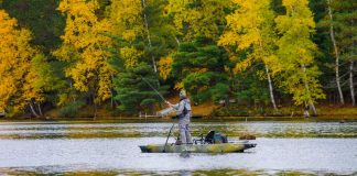 kayak angler stands and casts while fishing in Rainy River