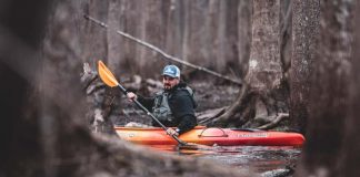 man paddling a sit inside fishing kayak