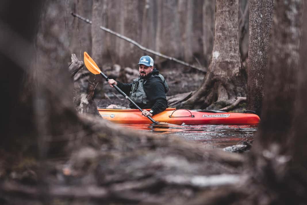 man paddling a sit inside fishing kayak