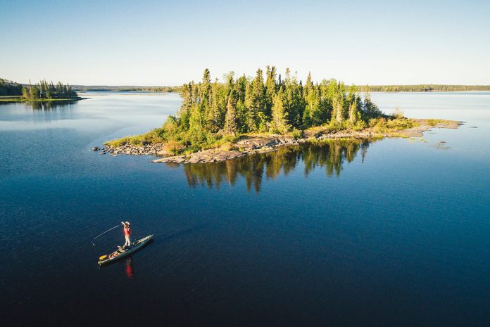 Lone kayaker paddling to an island in blue waters