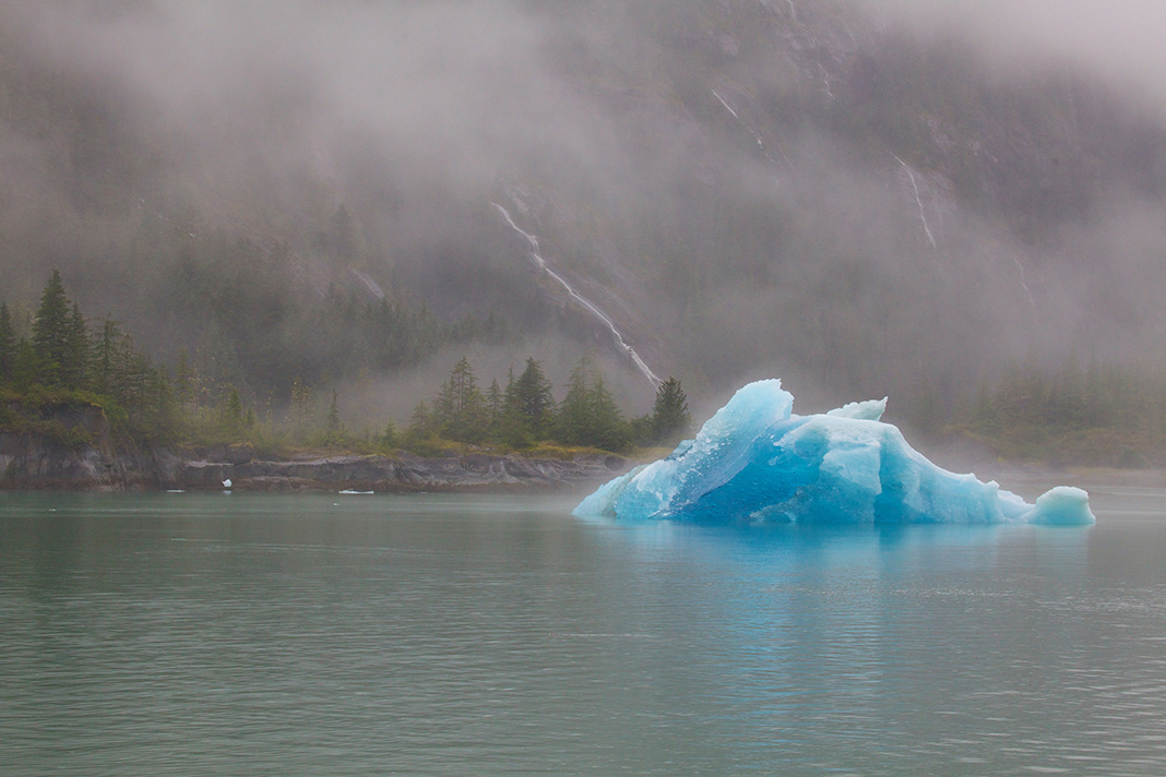 Vibrant iceberg in the lake with low-lying clouds
