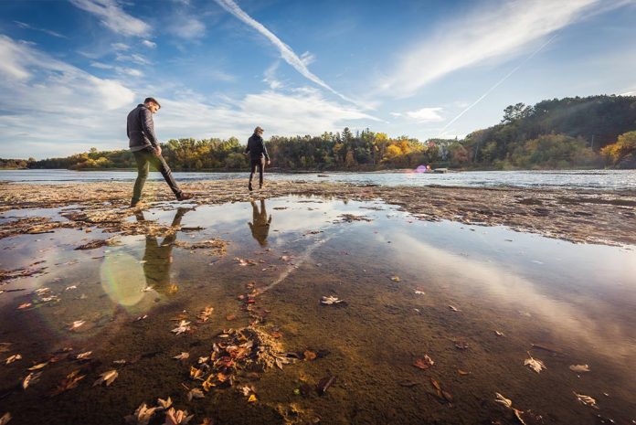 Two people walking next to a river.