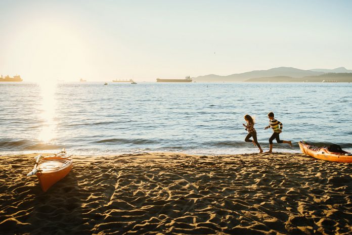 People running on the beach, a kayak on the shore