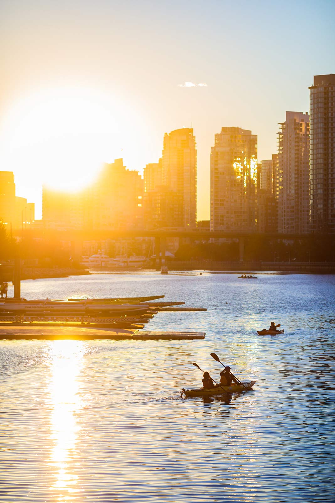 Kayakers paddling towards the city sunset