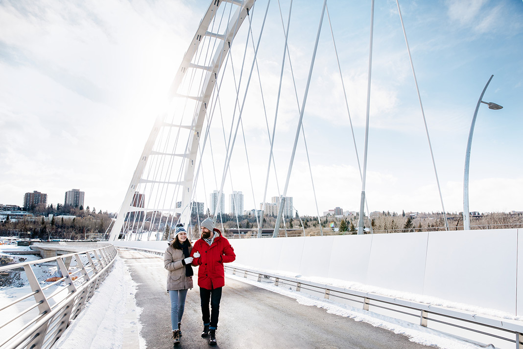 Two people standing on a bridge over a frozen river