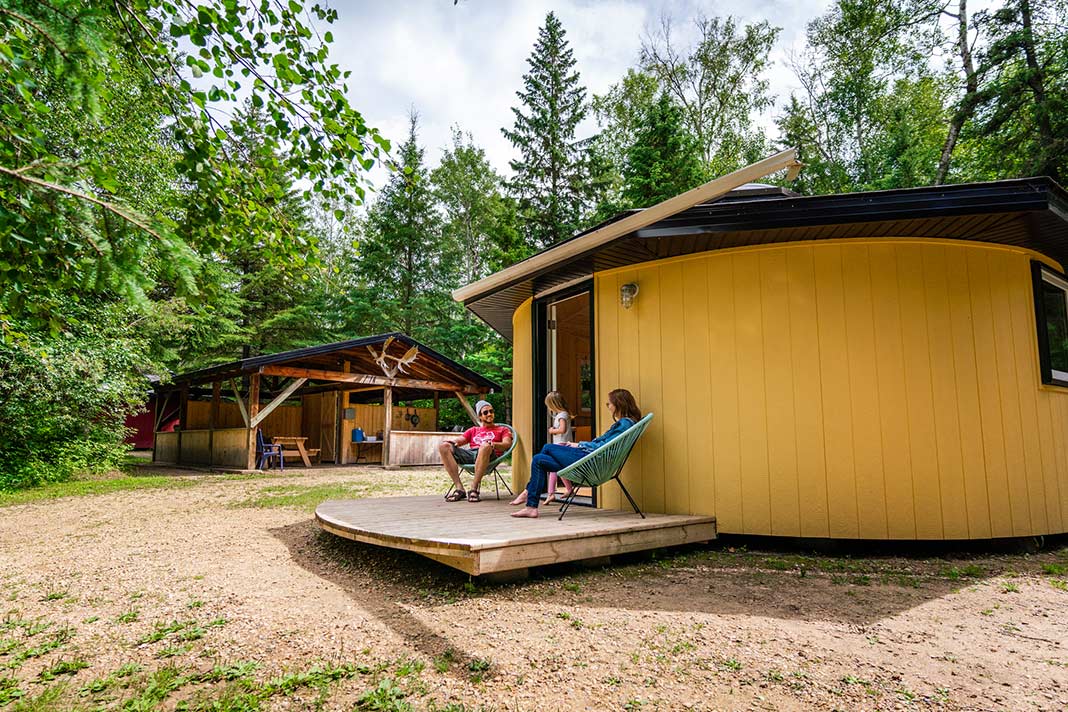 People sit outside a yurt at Elk Island Retreat while camping near Edmonton