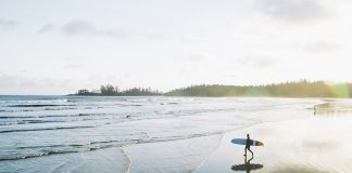 A lone surfer walking the wavey beaches of Vancouver Island