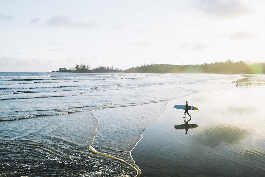 A lone surfer walking the wavey beaches of Vancouver Island