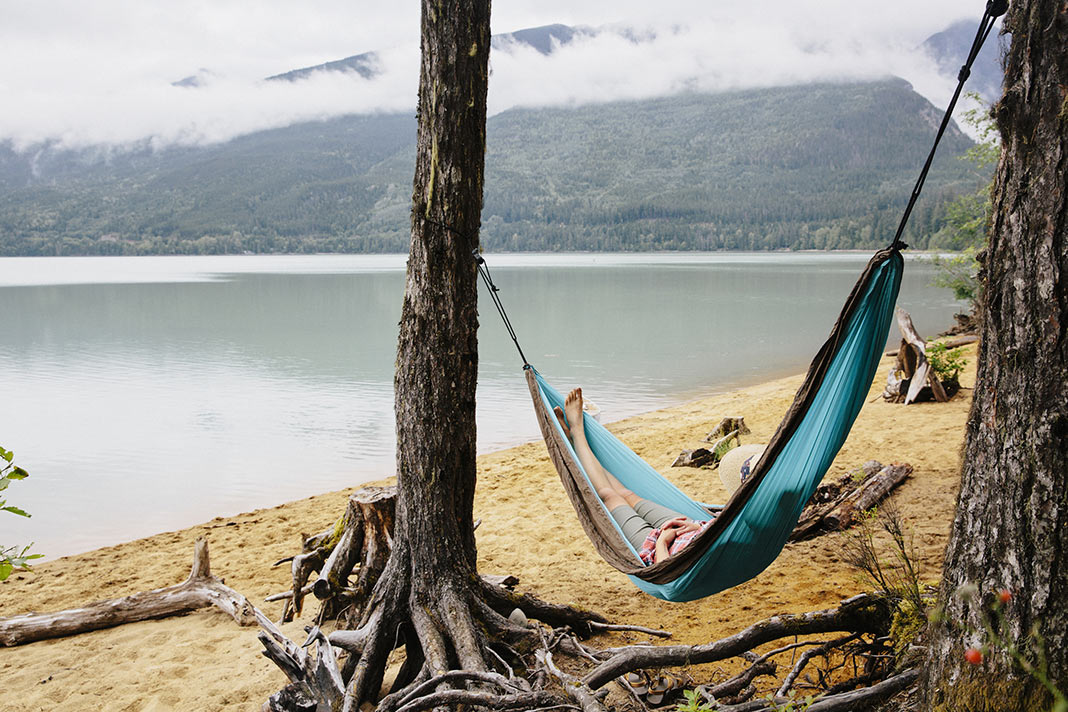Person naps in a hammock while camping on a Vancouver Island beach