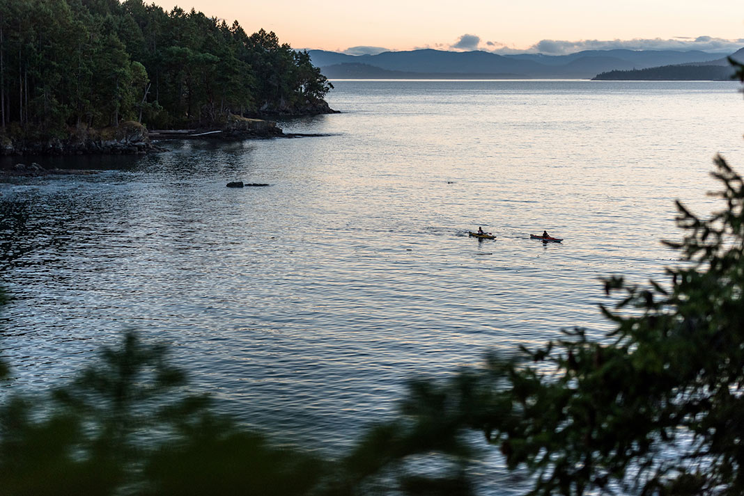 Kayakers in the distance on the waters at dusk