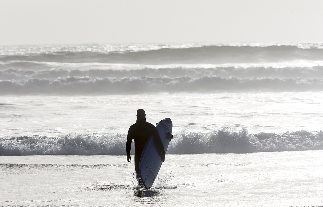 A surfer heading into the water at Tofino