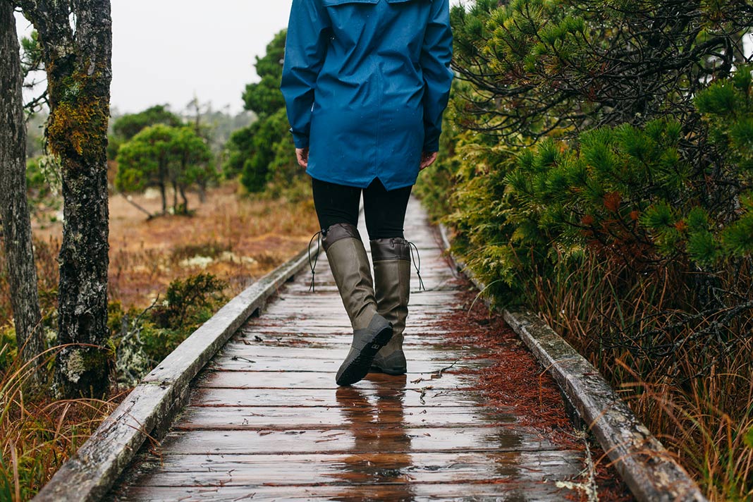 A person walks on a boardwalk in Tofino on a rainy day