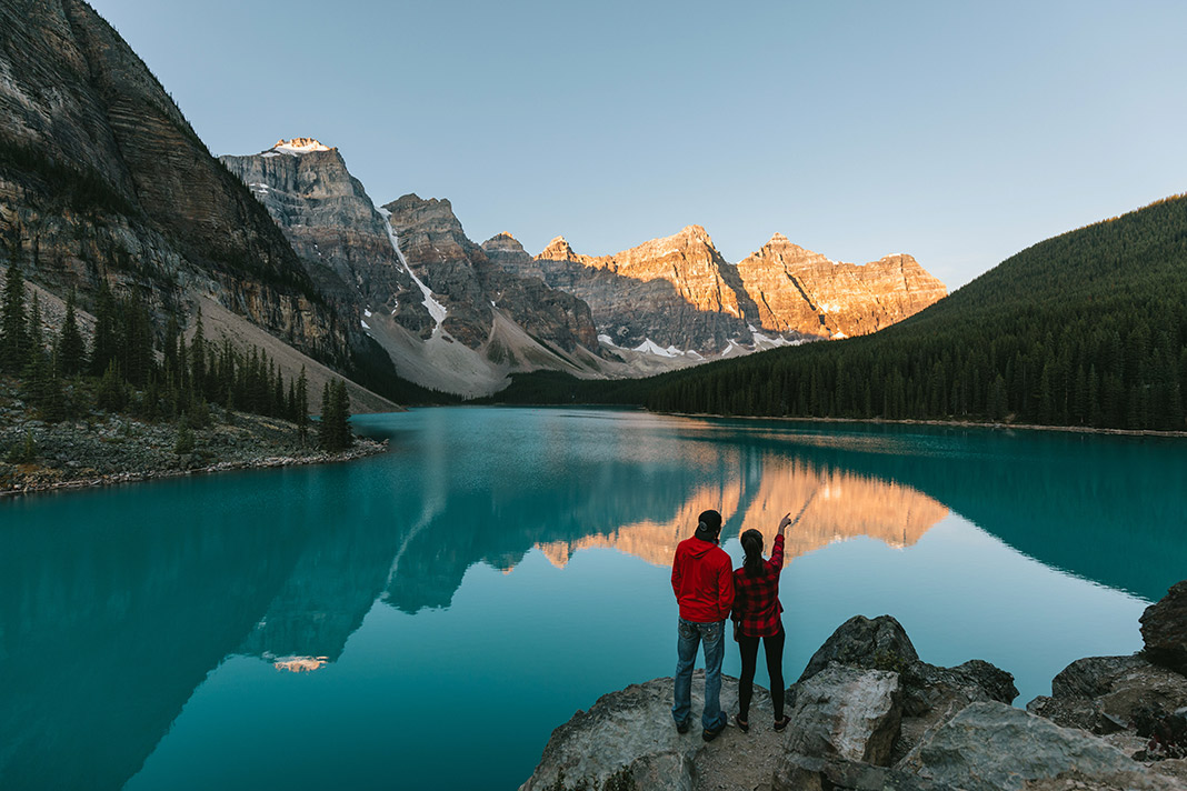 Two people standing on the shore of Moraine Lake