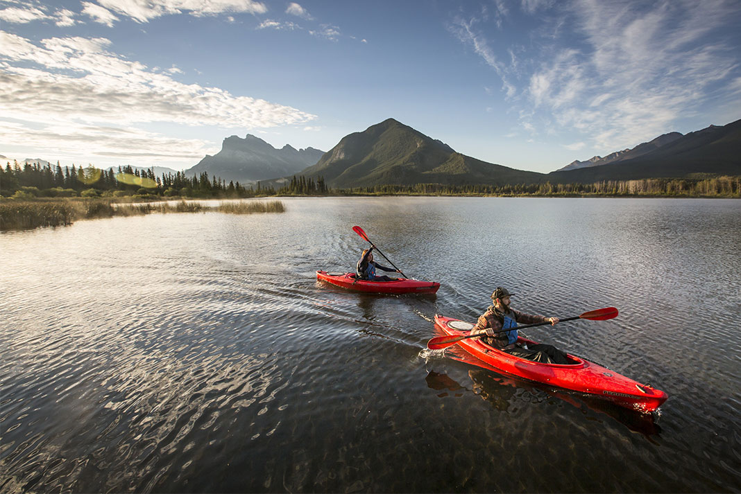 Two kayakers on the Vermillion Lakes of Banff, mountains looming in the background