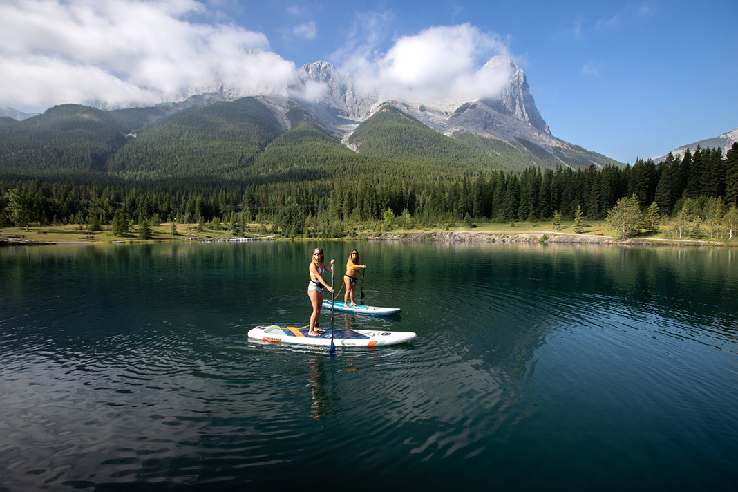 Two standup paddleboarders on the green waters of the Bow River