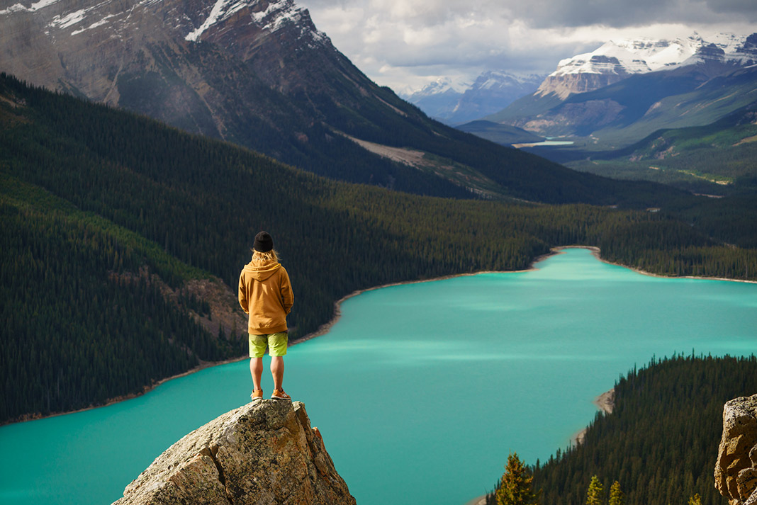 A person stands on a rock overlooking Moraine Lake