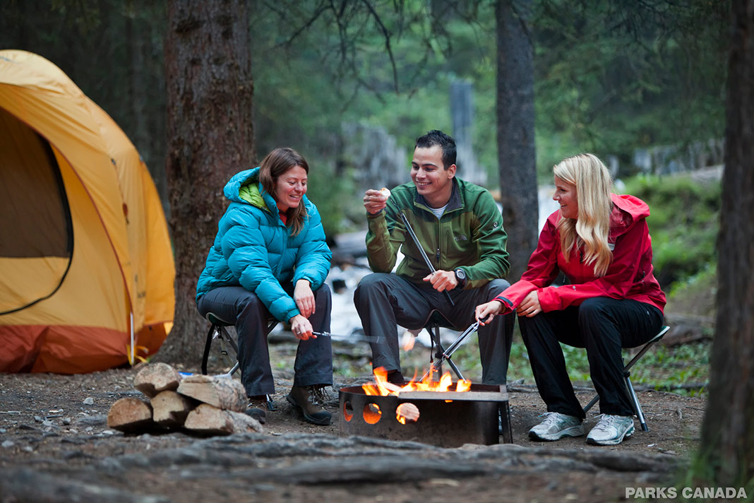 Three people enjoying the campfire in the woods