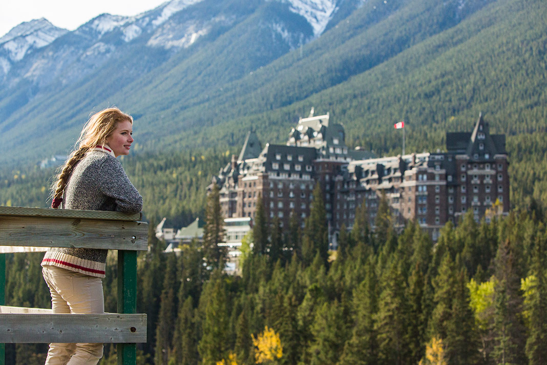 A woman stands on the edge of a viewpoint, the Fairmont Hotel in the background