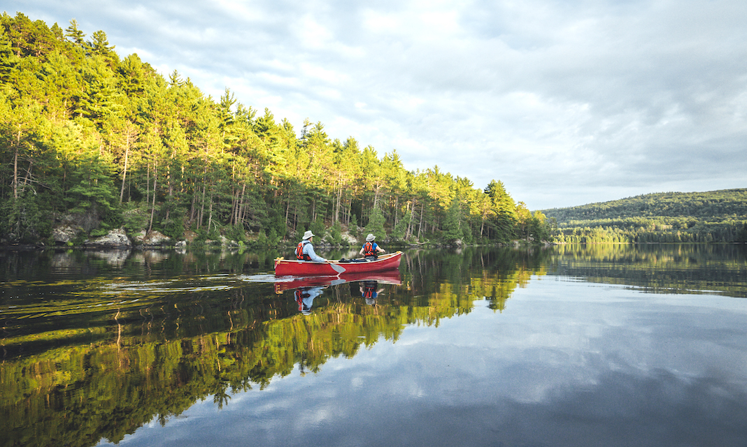 Two people paddling a red canoe on a calm lake