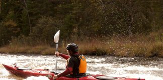 A man tackles the rapids of Riviere Rouge in a red kayak