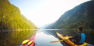 Two kayakers paddle down a river valley in Quebec