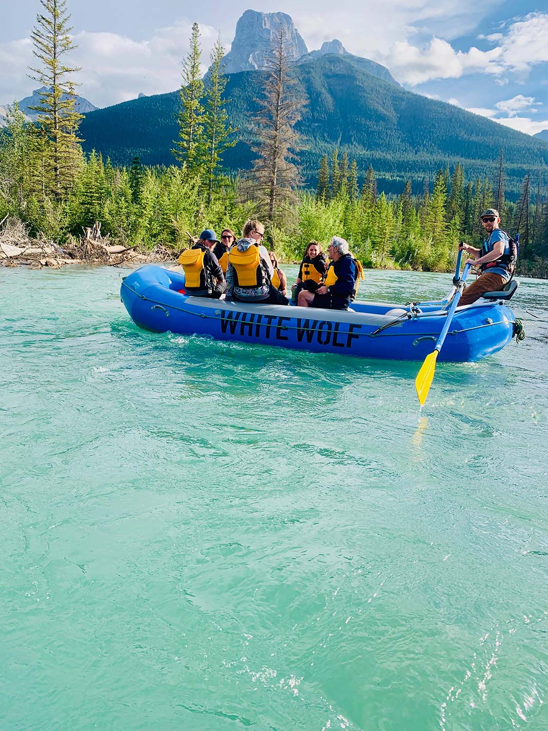 People in a blue raft with mountain in background