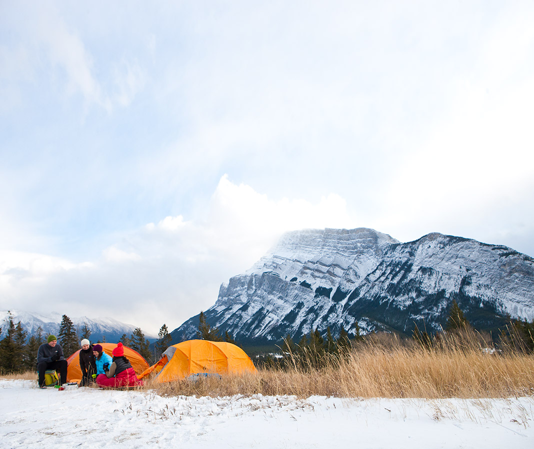 two tents set up in winter landscape with mountain in background