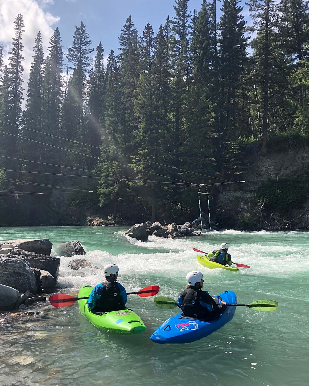 Three people whitewater kayaking on river