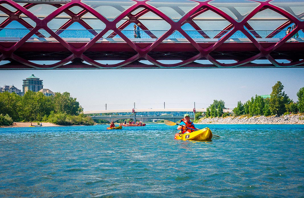 Kayakers on river going under a bridge crossing the water