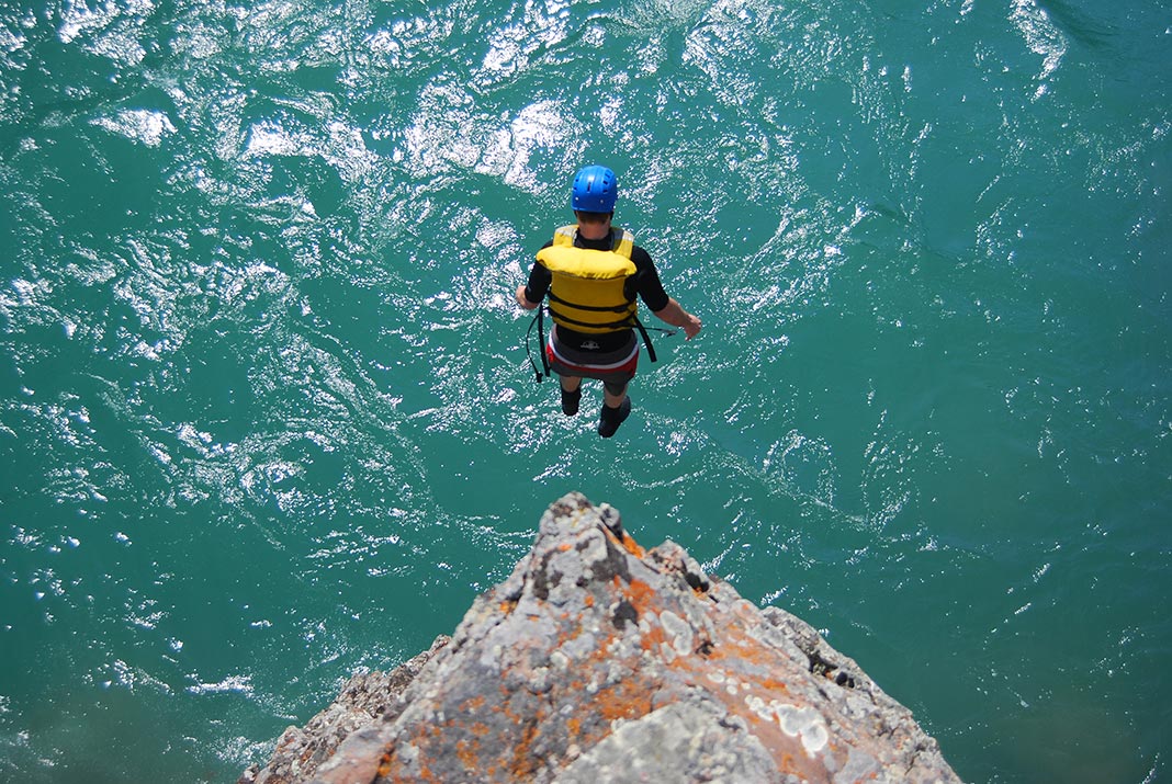 Overhead view of person jumping from cliff in to the river below