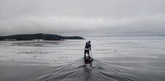 Man on a paddleboard on ocean on a gray day.