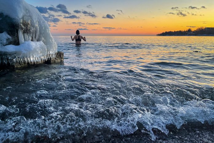Woman wading into lake in the wintertime.