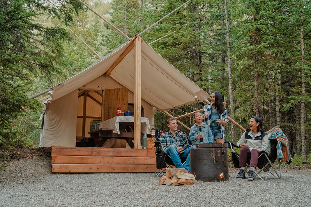 Group of people sitting in front of glamping tent