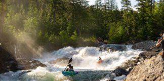 Two whitewater kayakers paddling down rapids.