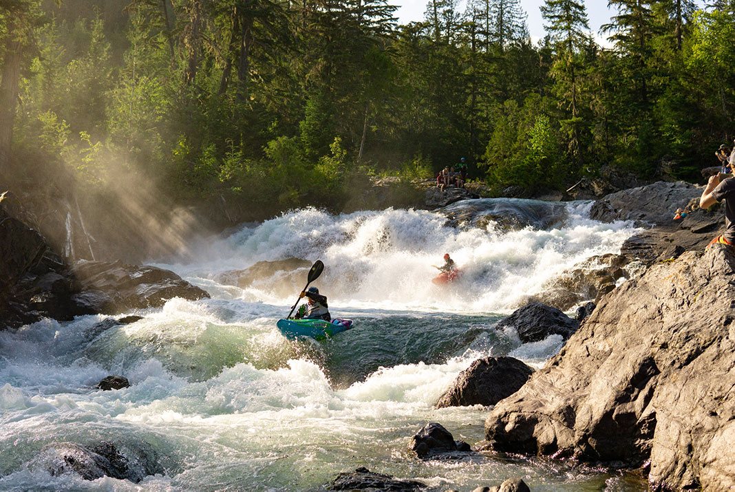 Two whitewater kayakers paddling down rapids.