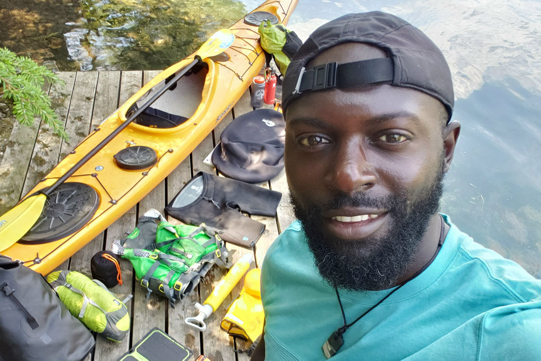 Man taking a selfie with kayak and gear laid out on dock next to water.