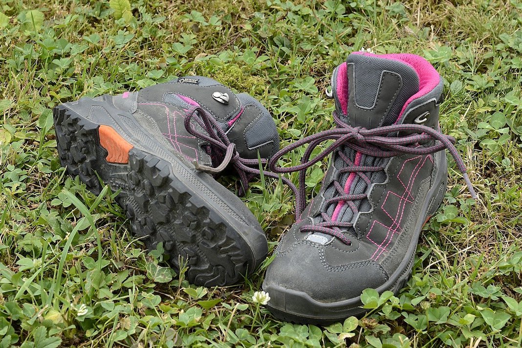 Pair of grey and pink hiking boots on the grass.