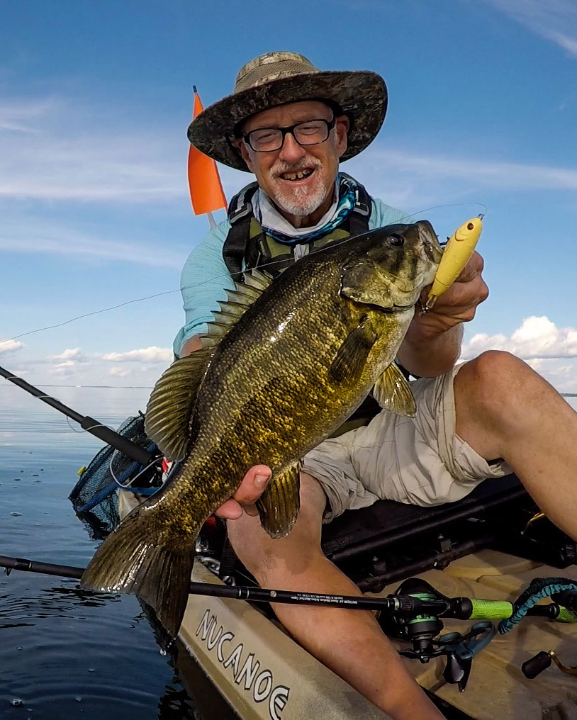 Minnesota angler holds up a smallmouth bass he caught while kayak fishing